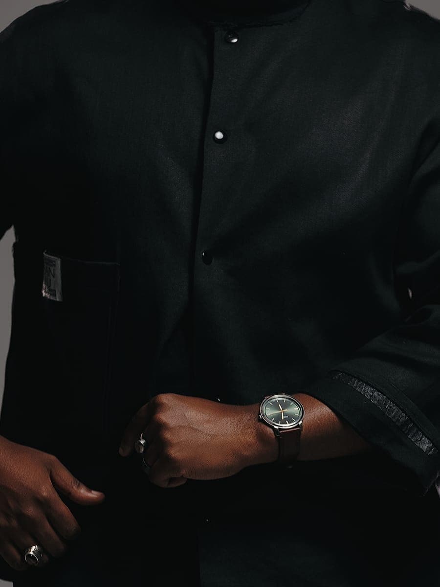 JOĒHUMAN's hands and watch, dressed in black